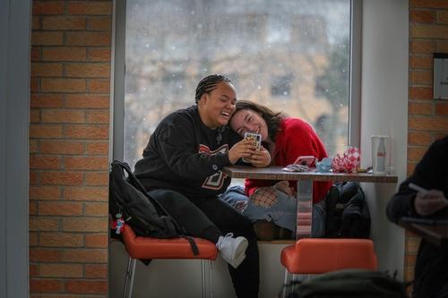 Two students enjoying social media during lunch