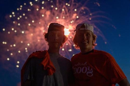 Two students with fireworks in background