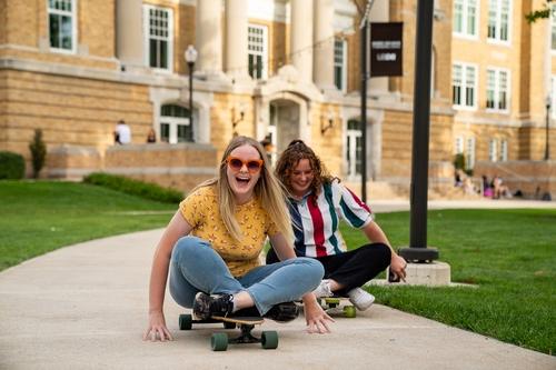 Two students skateboarding outside