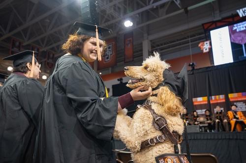 Student hugs service dog at commencement